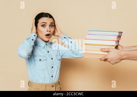 shocked student in denim shirt near books on beige Stock Photo