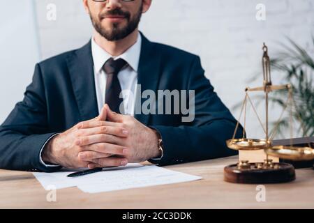 cropped view of bearded lawyer sitting with clenched hands at desk Stock Photo
