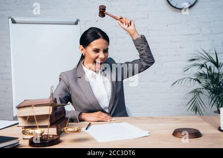 selective focus of excited judge holding gavel near documents, scales and books Stock Photo