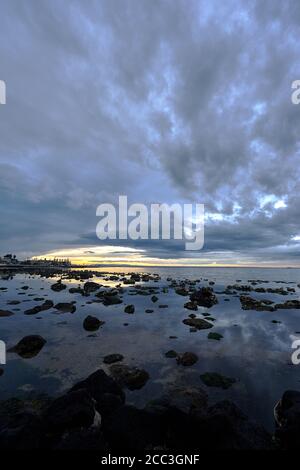 quiet flat seas under a dramatic brooding sky Stock Photo