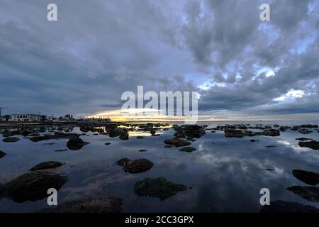quiet flat seas under a dramatic brooding sky Stock Photo