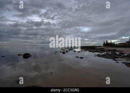 quiet flat seas under a dramatic brooding sky Stock Photo