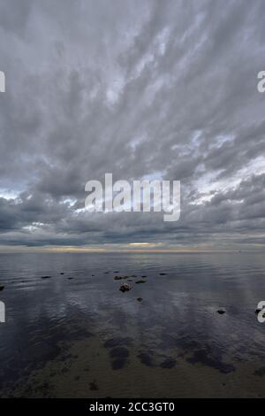 quiet flat seas under a dramatic brooding sky Stock Photo