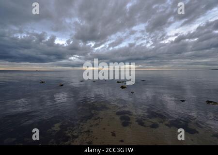 quiet flat seas under a dramatic brooding sky Stock Photo