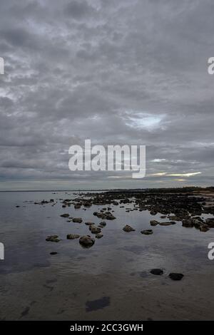 quiet flat seas under a dramatic brooding sky Stock Photo