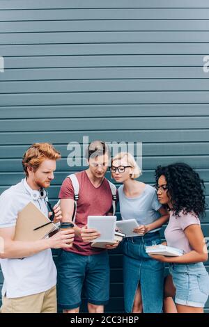 Multiethnic students with books using gadgets on urban street Stock Photo