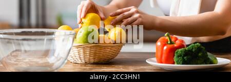 website header of woman touching lemons near vegetables on plate Stock Photo
