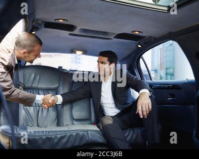 Businessmen Meeting In Limousine And Shaking Hands Stock Photo