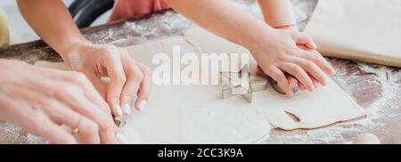 partial view of woman and child cutting out cookies from rolled dough near star-shaped mold, panoramic concept Stock Photo