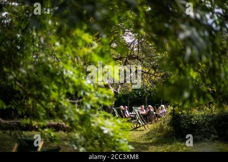 A group of people sit on deckchairs in Grantchester, near Cambridge, as the warm weather continues. Stock Photo