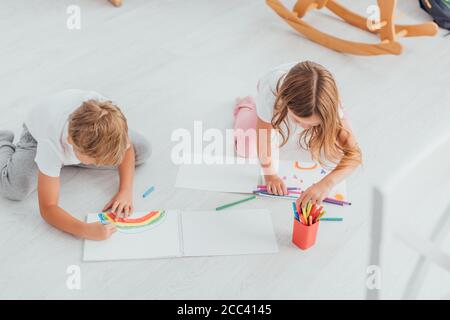 high angle view of brother and sister in pajamas sitting on floor and drawing with felt pens Stock Photo