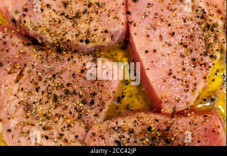 Tuna steaks marinated in gourmet sauce with black pepper, lemon and olive oil. Close-up top flat view. Stock Photo