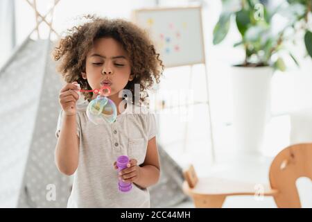 curly african american kid blowing soap bubbles Stock Photo
