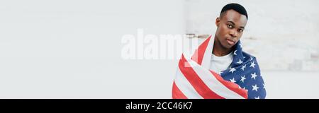 horizontal image of african american man covered with flag of american looking at camera Stock Photo