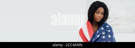 horizontal image of african american woman covered with flag of american looking at camera Stock Photo