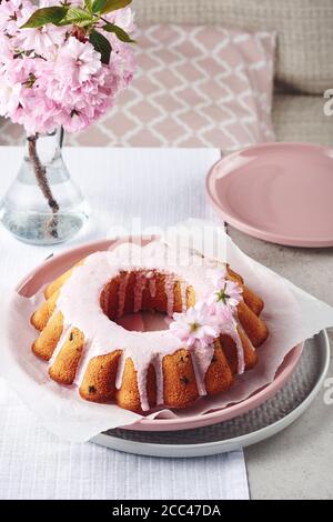 Festive Bundt cake with pink glaze, decorated with cherry flowers. Stock Photo