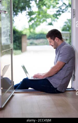 Businessman Working From Home On Laptop During Pandemic Lockdown Stock Photo