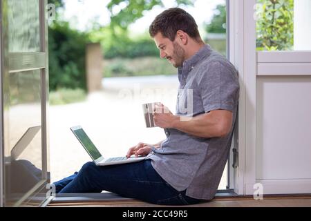Businessman Working From Home On Laptop During Pandemic Lockdown Stock Photo