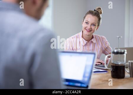 Business Couple Working From Home Sitting At Table During Pandemic Lockdown Stock Photo