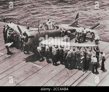 Personnel of the Enterprise aircraft carrier (CV-6) places the Douglas SBD Dauntless dive bomber from the US VB-6 bomber squadron on the edge of the f Stock Photo