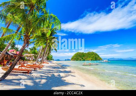 Beach with white sand, coconut palms and turquoise water in El Nido province, Palawan island in Philippines Stock Photo