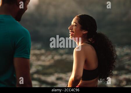 Couple in fitness wear relaxing after a run. Close up of a smiling fitness woman talking to her running partner after a run. Stock Photo