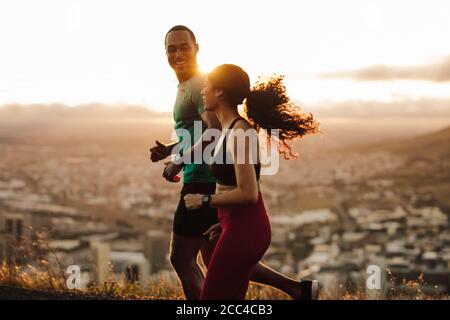 Fitness couple going for sunrise running. Fitness man and woman running on road.