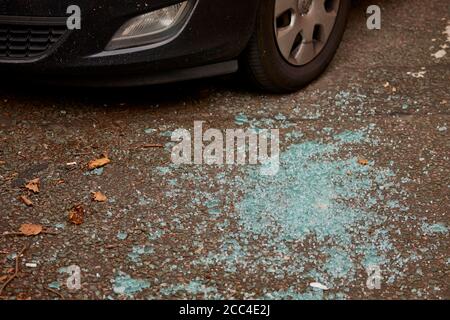 Broken glass on the road around a parked car Stock Photo