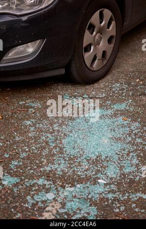 Broken glass on the road around a parked car Stock Photo