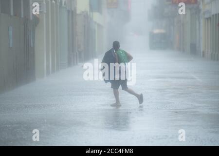 (200819) -- MACAO, Aug. 19, 2020 (Xinhua) -- A man walks in the rain on a road in Macao, south China, Aug. 19, 2020. China's Macao Special Administrative Region has downgraded its typhoon signal from highest No.10 level to No.8 on Wednesday at 7:30 a.m. local time, but the low-lying areas near the coastline were flooded, as Typhoon Higos had made landfall in the neighboring city of Zhuhai in the morning. Credit: Xinhua/Alamy Live News Stock Photo