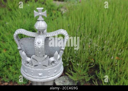 Silver coloured metal crown isolated on grass with copy space Stock Photo