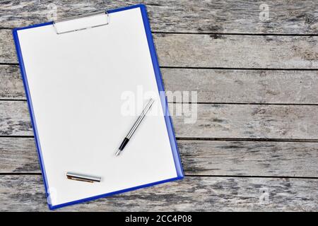 Clipboard with blank white paper with fountain pen on a wood table Stock Photo