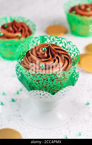 Chocolate cupcakes with green sugar sprinkles on light background Stock Photo