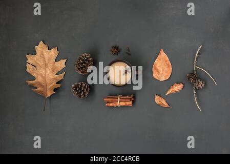 Autumn Leaves and cup of hot drink creative flat lay. Fall Background. Dried leaves, pine cones and coffee or tea on black, Thanksgiving day cozy conc Stock Photo