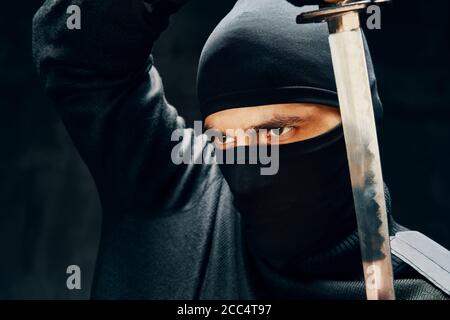 Fighting ninja posing with a sword over black background. japanese fighter concept Stock Photo