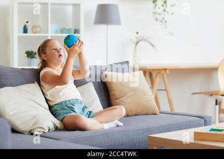 Down syndrome girl playing with model of planet while sitting at home Stock Photo