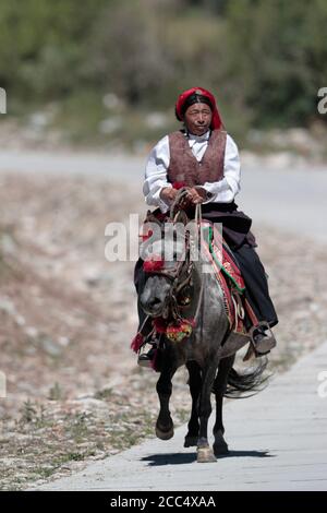 Tibetan Horseman on a grey pony, near Yushu, Qinghai Province, China 24th August 2017 Stock Photo