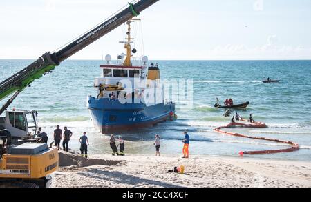 18 August 2020, Schleswig-Holstein, Westerland/Sylt: Corrects the name of the ship to «MS Oland». Emergency forces are laying oil snakes around the survey ship «MS Oland», which is moored on the beach off Westerland on the North Sea island of Sylt. According to police, the ship probably struck a groyne during a survey trip, causing a water ingress. Photo: Daniel Bockwoldt/dpa Stock Photo