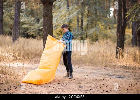 Autumn lifestyle of man inflates an inflatable orange sofa in forest. Relaxing and enjoying life on air bed banner format Stock Photo