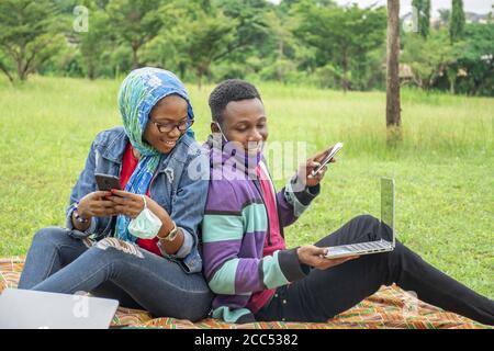 Young African students sitting in a park working on a college task together Stock Photo