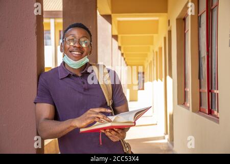 Portrait of a smiling African male student holding a book and smiling Stock Photo