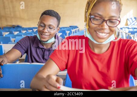 Shallow focus of two young African students wearing facemasks and studying in a classroom Stock Photo