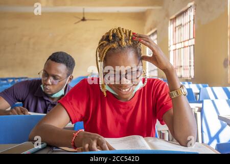 Shallow focus of two young African students wearing facemasks and studying in a classroom Stock Photo