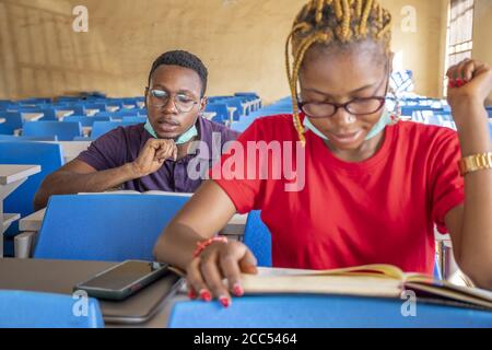 Shallow focus of two young African students wearing facemasks and studying in a classroom Stock Photo
