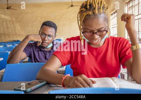 Shallow focus of two young African students wearing facemasks and studying in a classroom Stock Photo
