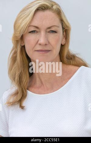 Studio portrait of an attractive middle aged blonde woman smiling on a white background Stock Photo