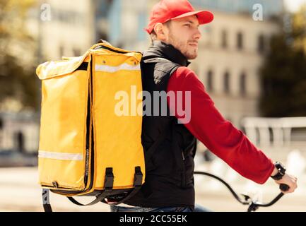 Delivery Guy Riding Bike Outdoors In Urban Area Delivering Food Stock Photo