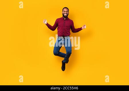 Happy black guy jumping and looking at camera Stock Photo
