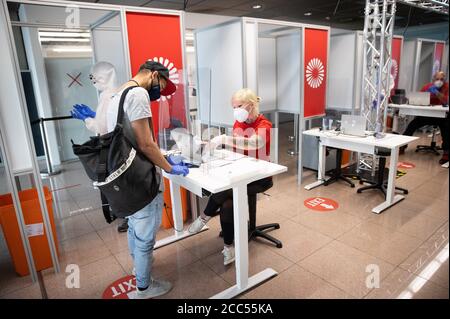 Hamburg, Germany. 19th Aug, 2020. An employee speaks to a holidaymaker at a media appointment in the new, commercial Covid 19 test centre at Hamburg Airport after he returns home. The offer of the commercial company Centogene is aimed at travellers returning from countries classified as non-risk areas by the Robert Koch Institute and at passengers who start their journey from Hamburg and require a certificate in their destination country. The results should be available within 24 hours and be digitally retrievable. Credit: Christian Charisius/dpa/Alamy Live News Stock Photo