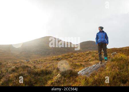 A person walking in Scottish countryside near the Allt Coire Rooill river in Torridon, Scotland Stock Photo